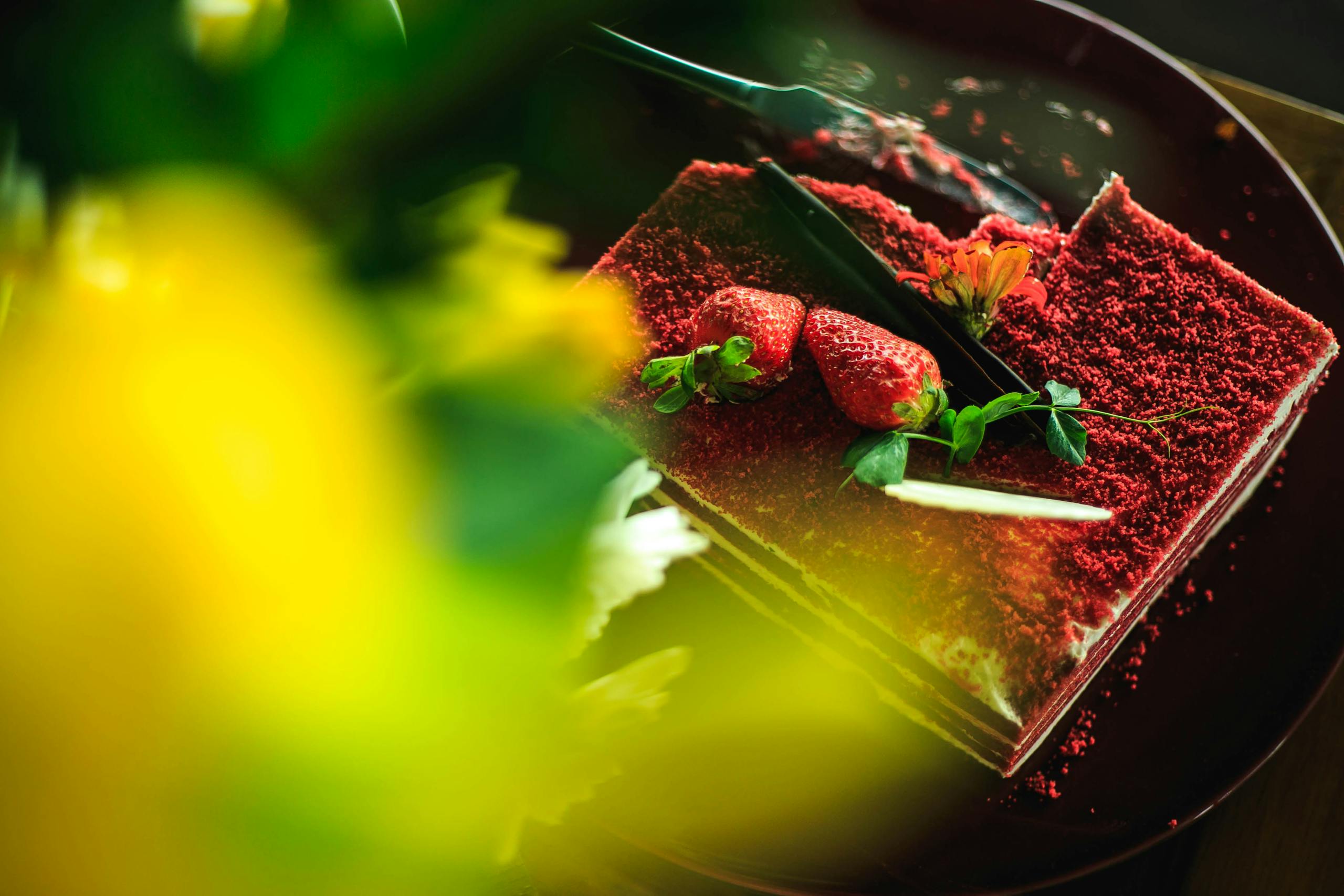 Close-up of a rich red velvet cake topped with fresh strawberries and cream cheese frosting.