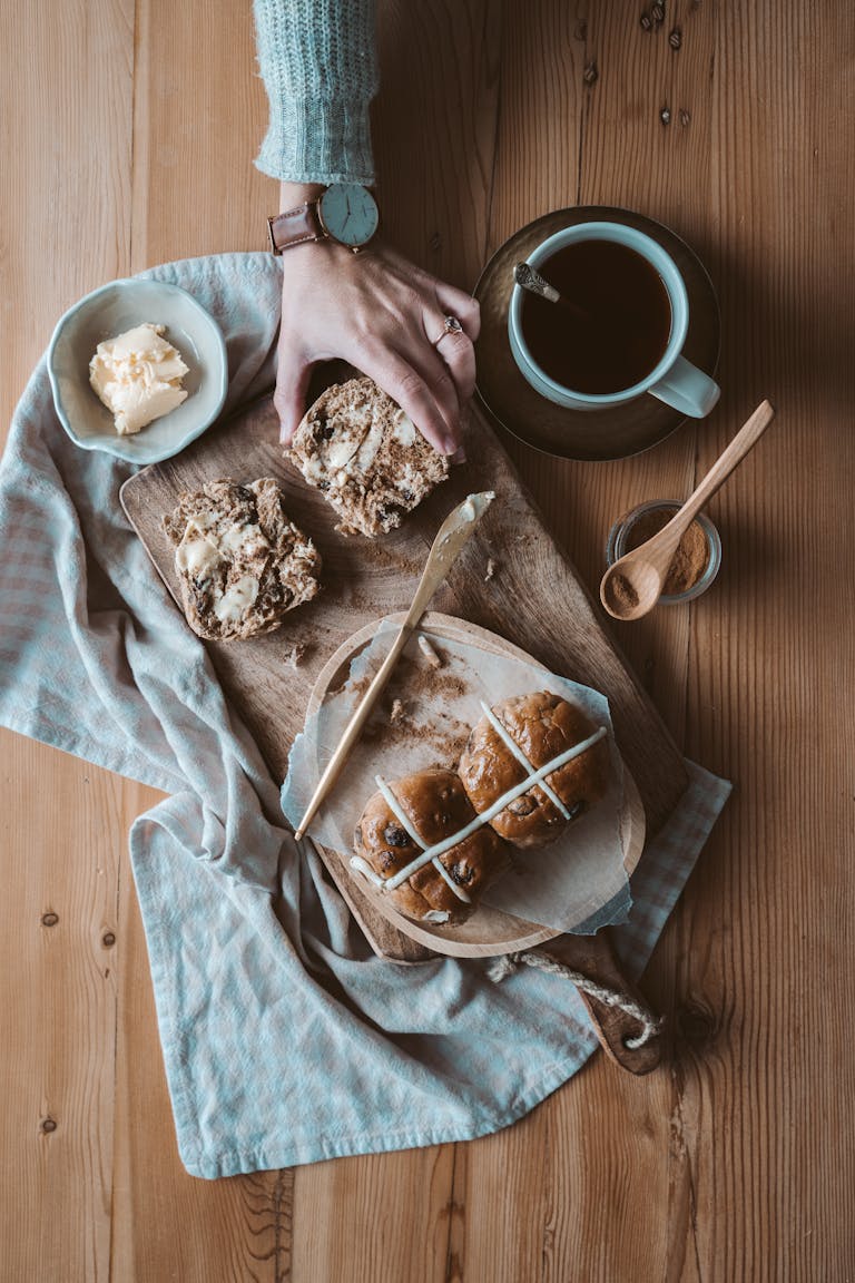 A cozy rustic breakfast setup with buns and tea on a wooden table.